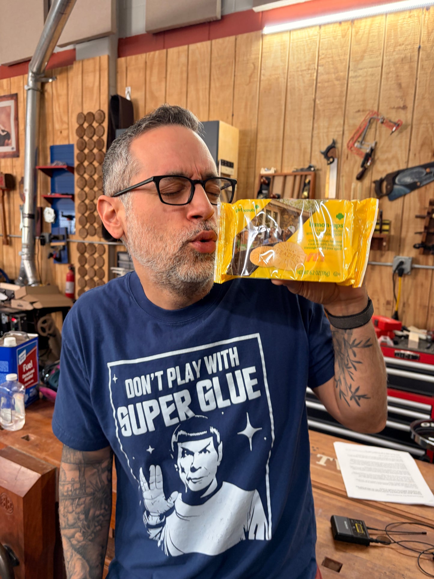 Man wearing a blue shirt with text in a workshop setting kissing lemon up girl scout cookies