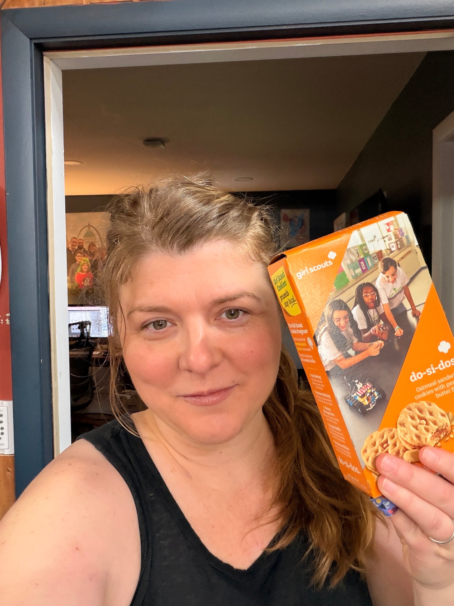 Woman holding a box of Do-Si-Do cookies in an indoor setting