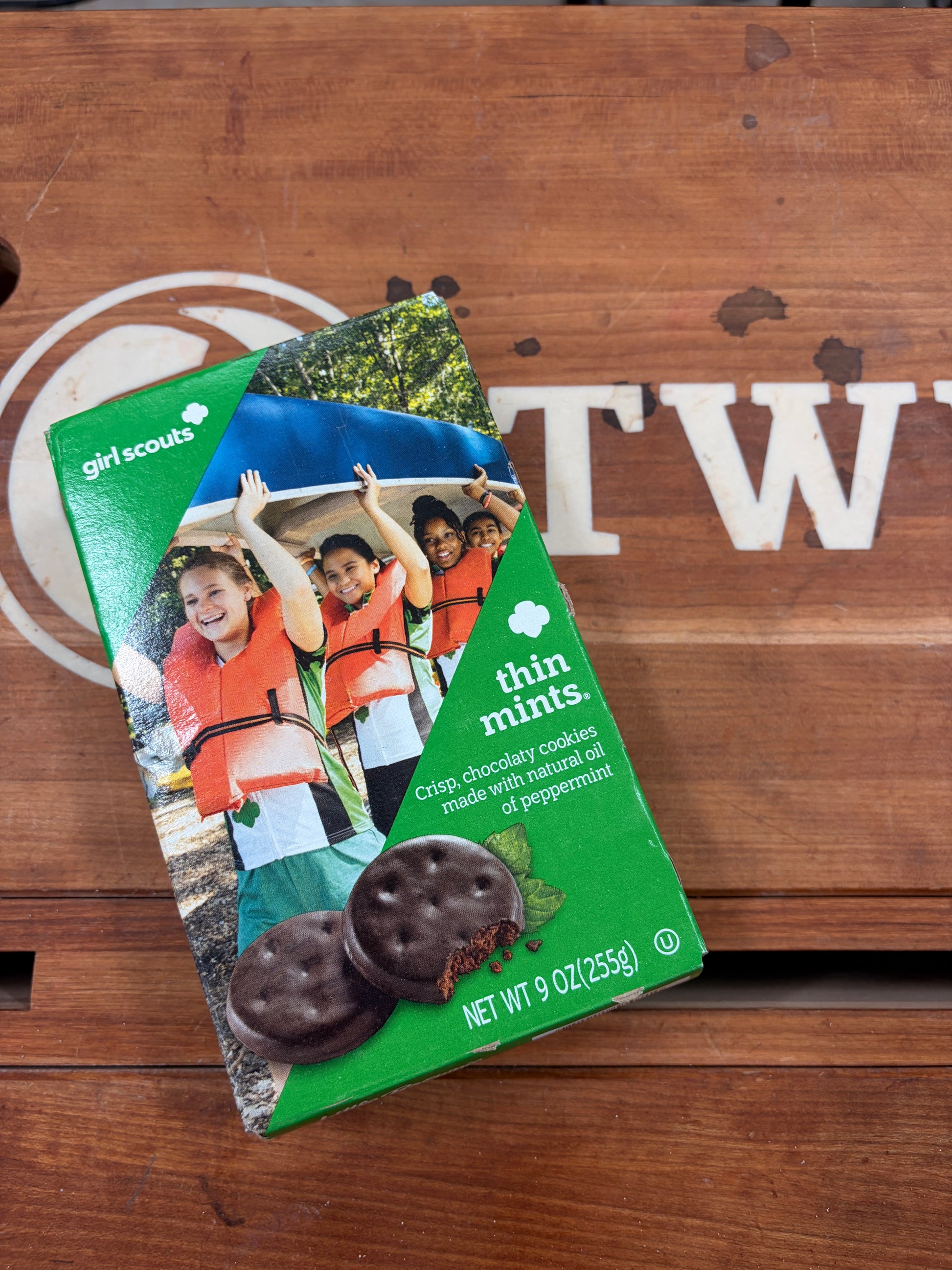 Packaged thin mints on a wooden surface with a visible logo.